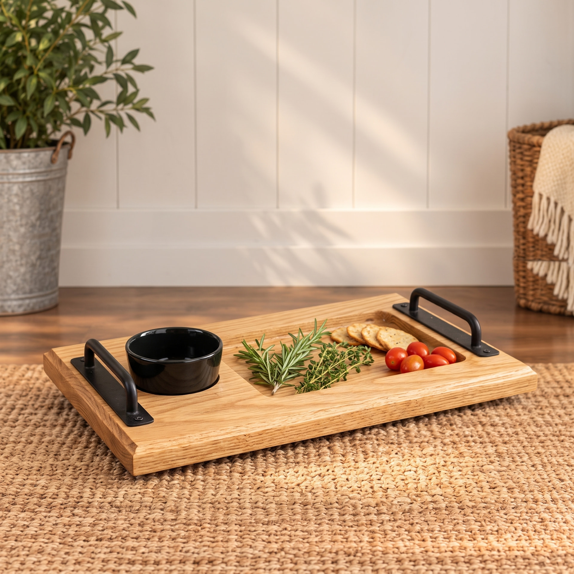 White oak charcuterie board with iron handles, a black bowl, herbs and crackers